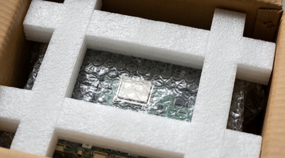 foam pads and bubble wrap cushioning a fragile electronic component inside a crate